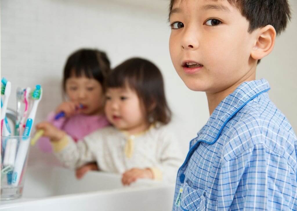 Children using kids toothpaste in the bathroom.