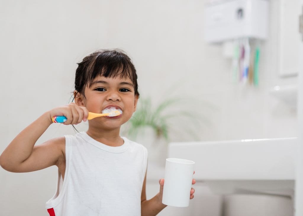 A child brushing their teeth with kids toothpaste.